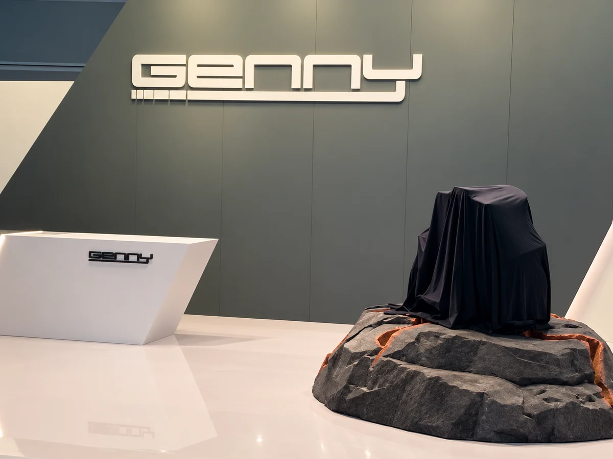 Genny-Schriftzug am Messestand, davor die noch verhüllte Genny Zero XR auf einem Steinpodest vor der Weltpremiere