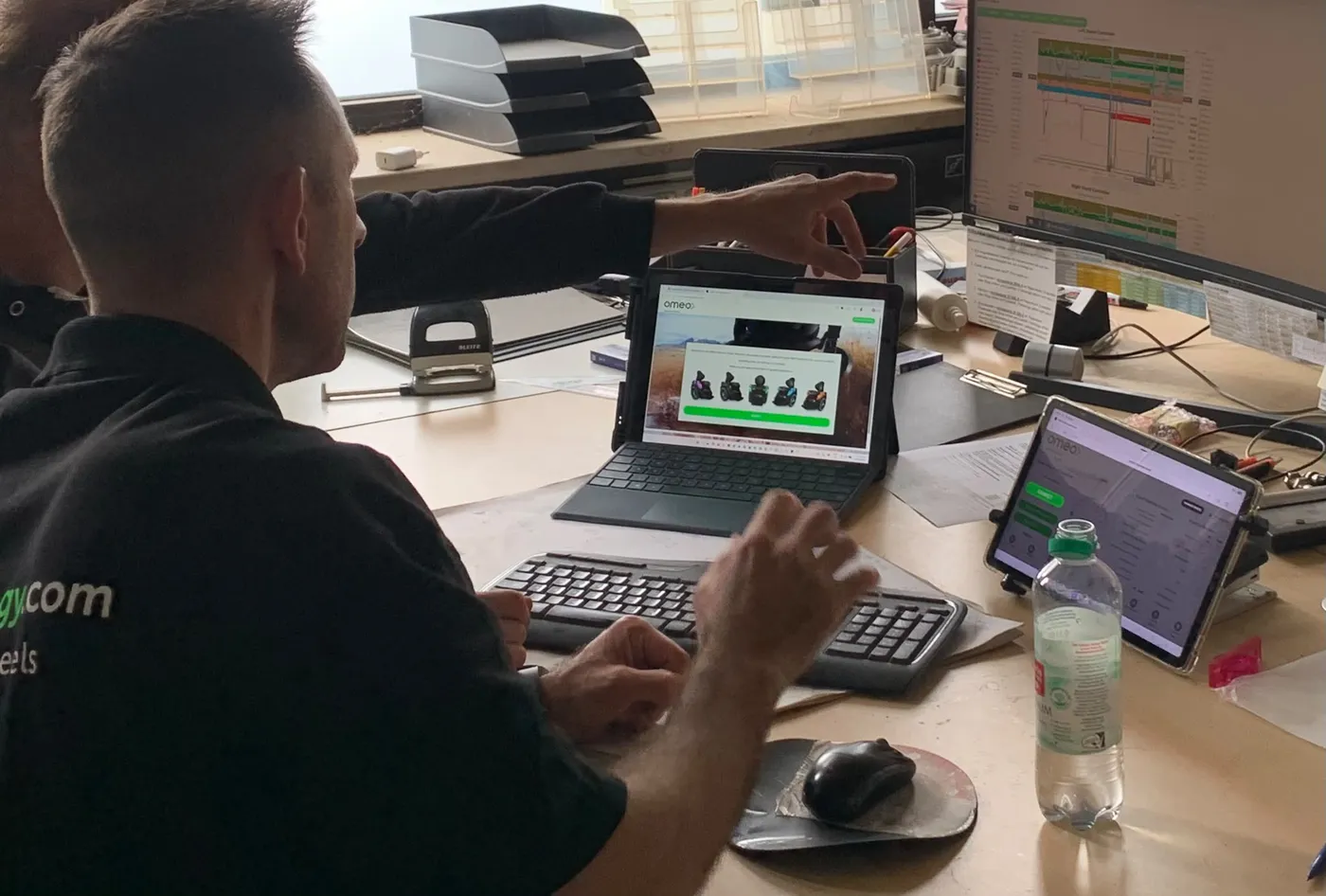 PT-Pro-Mitarbeiter arbeitet am Laptop mit der Omeo-Diagnosesoftware und mehreren Tablets