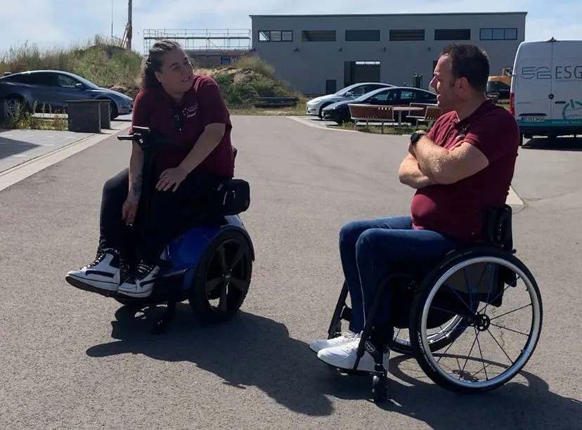 WIBO-Reha-Team im Gespräch – eine Mitarbeiterin auf dem Genny Zero, ein Kollege im Rollstuhl
